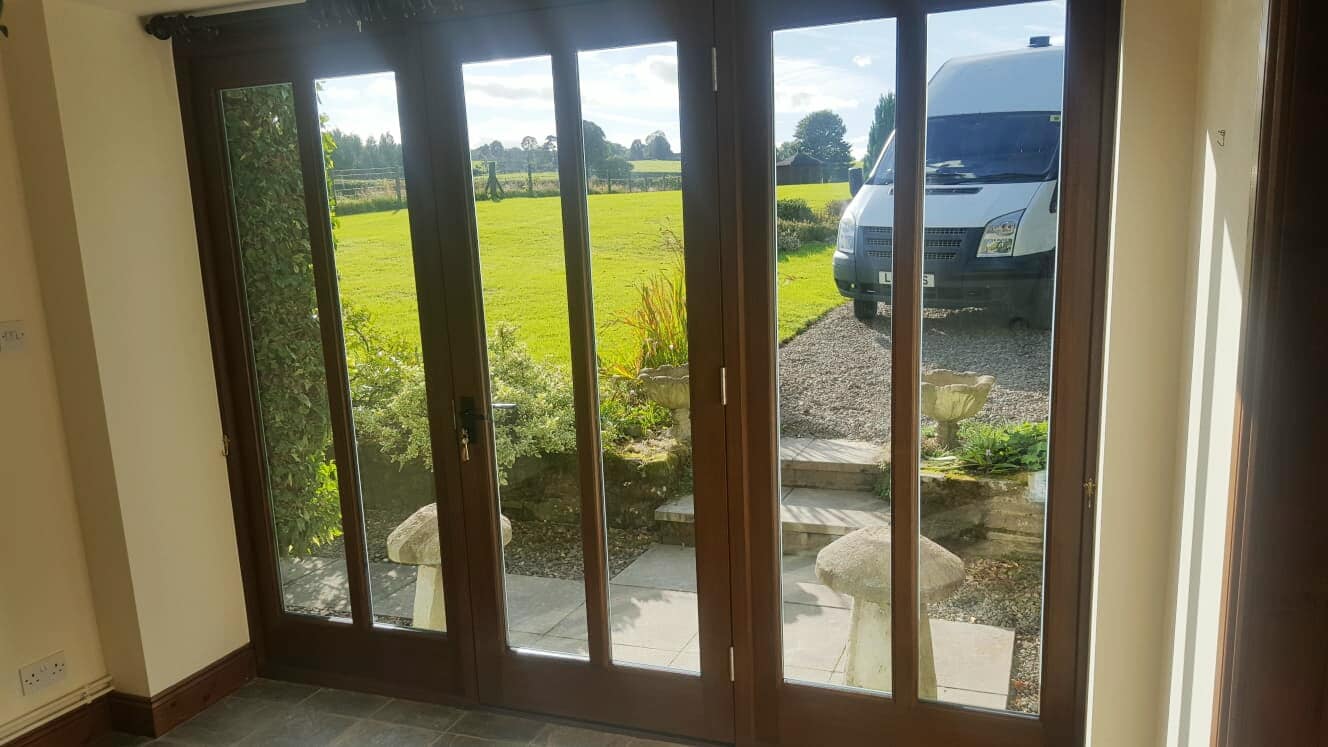 Hardwood bi-fold doors opening onto a Powys field.